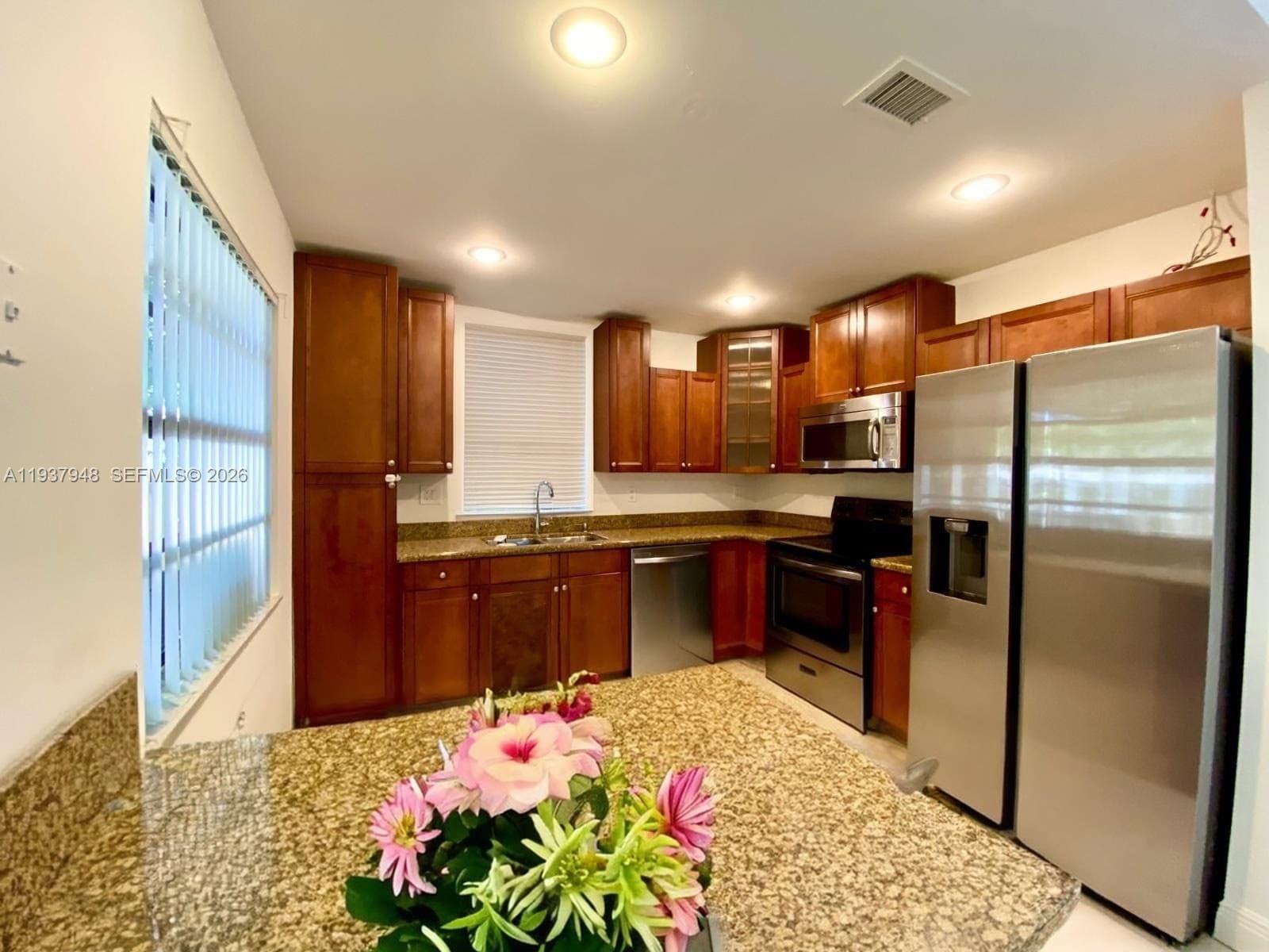 1297 Southwest 151st Avenue Sunrise, FL 33326 - Photo 8 of 12 a kitchen with stainless steel appliances kitchen island granite countertop a refrigerator and a sink