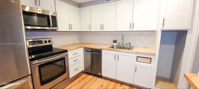 a kitchen with white cabinets stainless steel appliances and sink