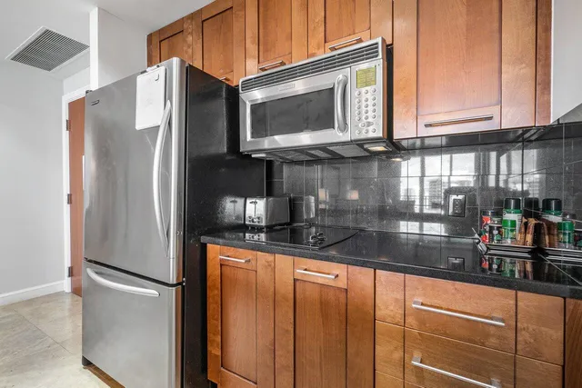 a kitchen with granite countertop a refrigerator and a stove top oven