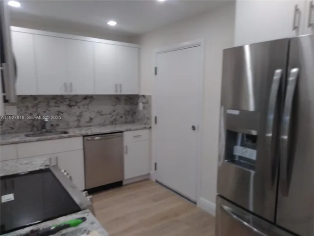 a kitchen with a refrigerator and a wooden floor