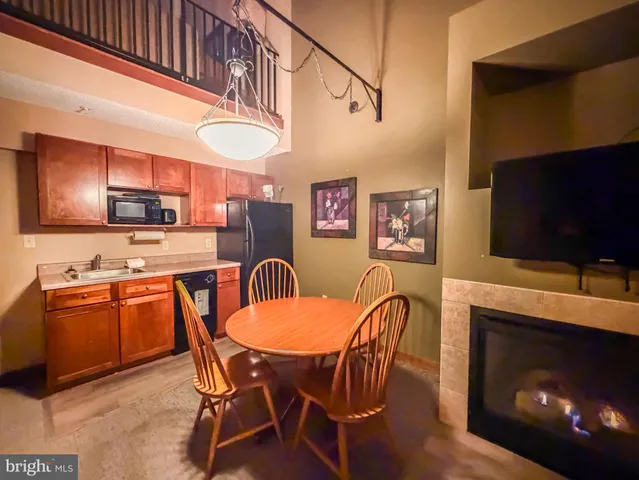 a kitchen with stainless steel appliances granite countertop a stove a refrigerator a kitchen island a dining table and chairs with wooden floor