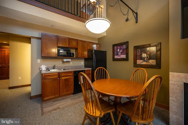 a kitchen with stainless steel appliances granite countertop a dining table and chairs a refrigerator with wooden floor