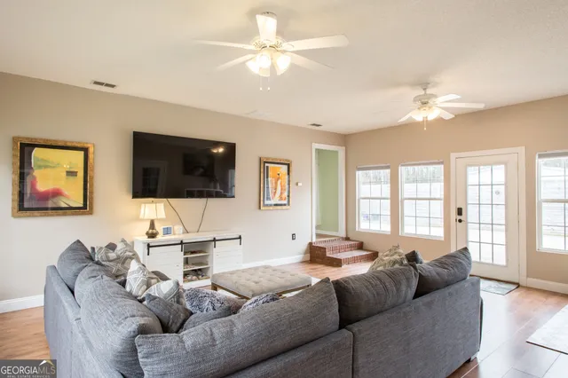 a living room with furniture a flat screen tv and a ceiling fan