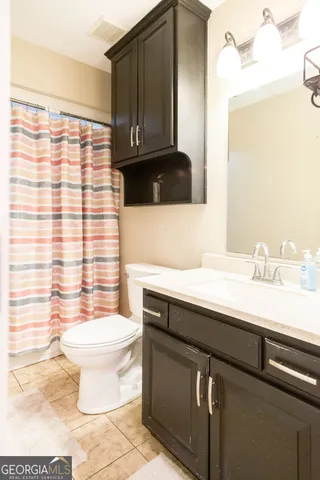 a bathroom with a sink a toilet a mirror and shower curtain