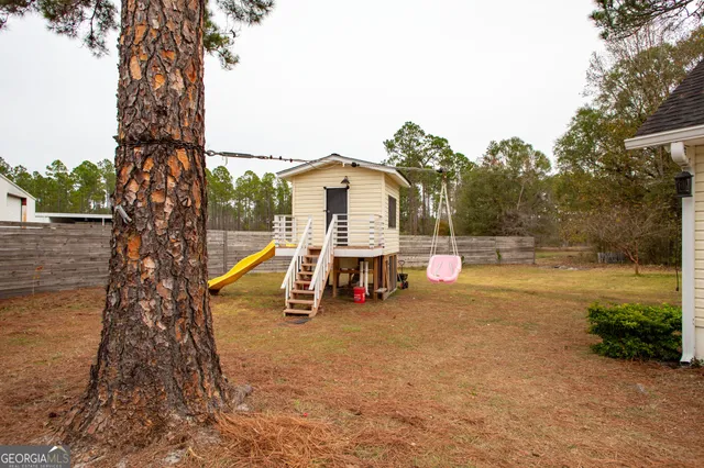 a view of a house with a yard and large tree