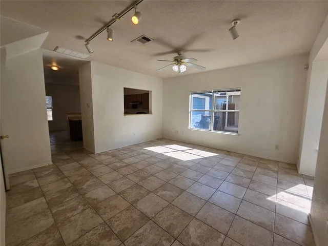 a view of an empty room and chandelier fan
