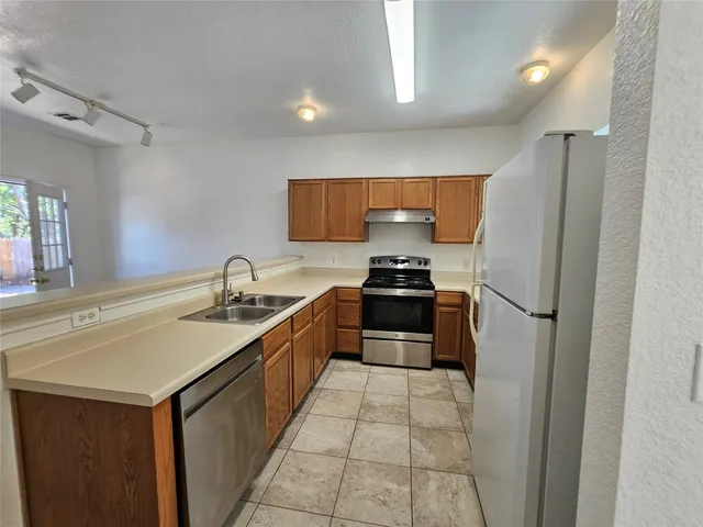 a kitchen with stainless steel appliances granite countertop a refrigerator stove a sink and a microwave