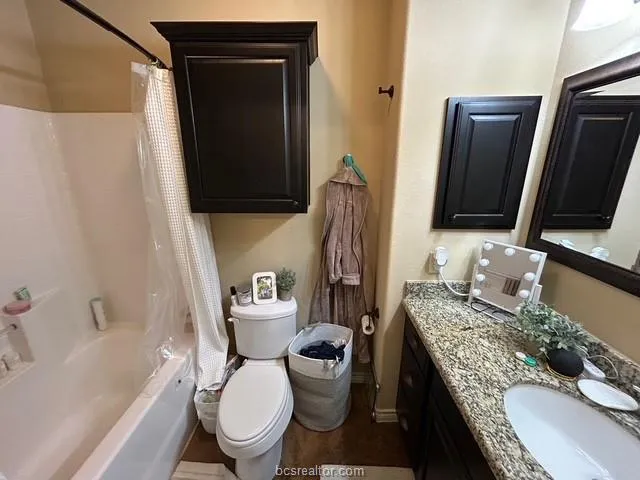 a bathroom with a granite countertop toilet sink and mirror