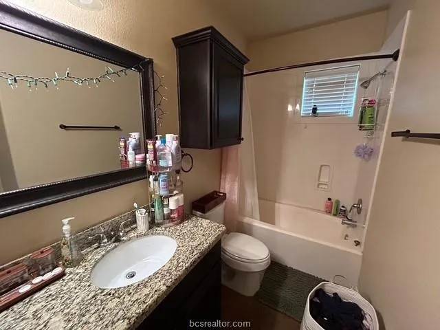 a bathroom with a granite countertop sink toilet mirror and bathtub