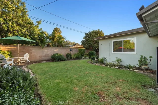 a backyard of a house with table and chairs under an umbrella