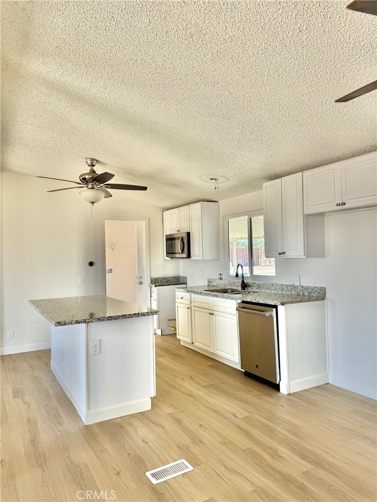 12782 Atsina Road Phelan, CA 92371 - Photo 5 of 18 a kitchen with granite countertop a white cabinets and refrigerator