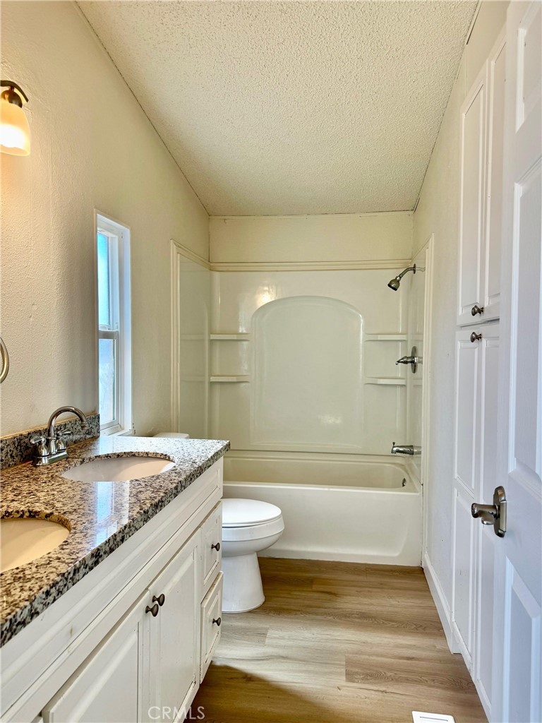 12782 Atsina Road Phelan, CA 92371 - Photo 10 of 18 a bathroom with a granite countertop sink a toilet and shower