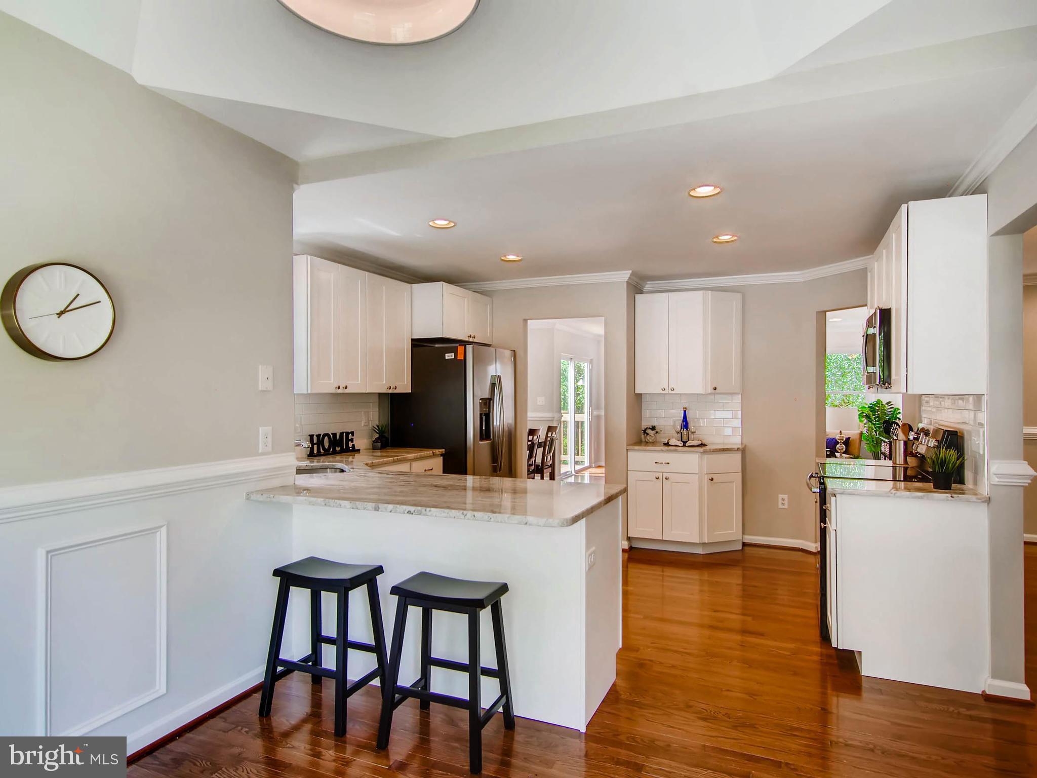 1606 Frederick Road Baltimore, MD 21228 - Photo 4 of 28 a kitchen with a dining table chairs refrigerator and microwave