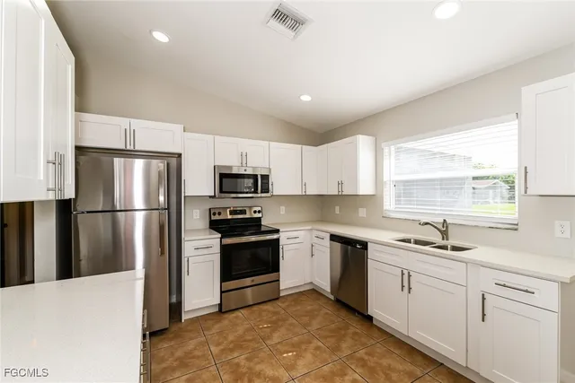 a kitchen with a sink stainless steel appliances and window