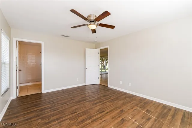 an empty room with wooden floor and a ceiling fan