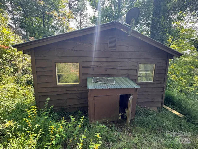 a brick house with a small yard plants and large tree