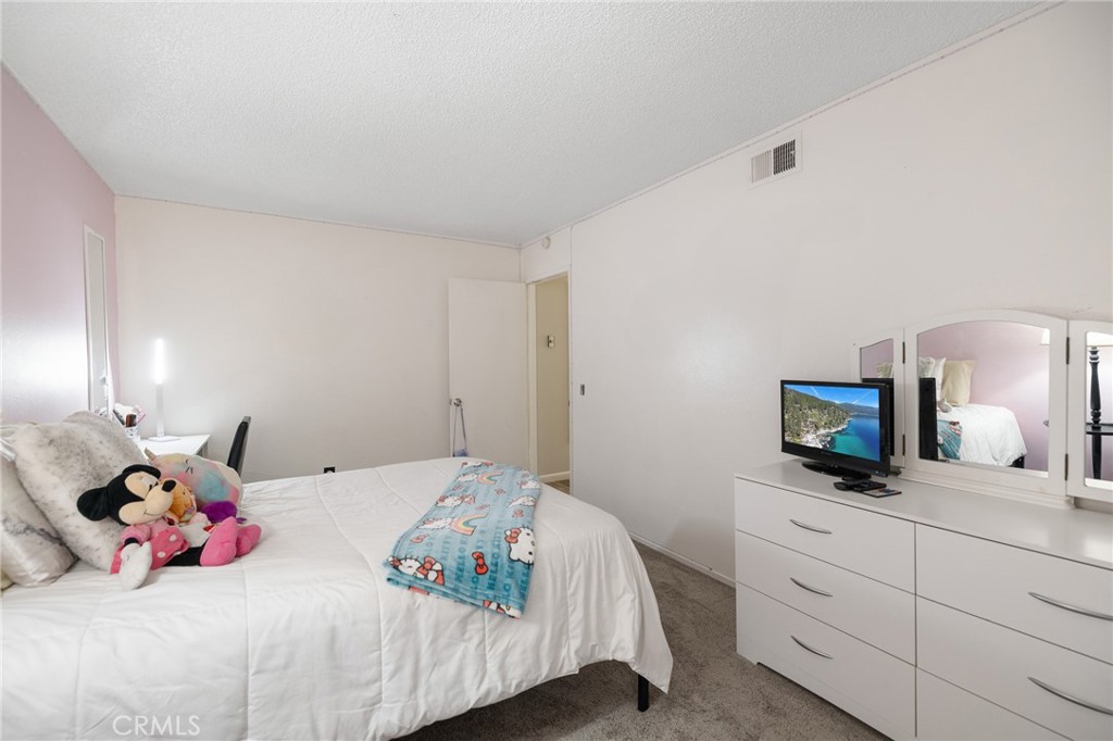 638 Eston Place Lancaster, CA 93535 - Photo 32 of 44 a bedroom with a bed and a flat tv screen on dresser