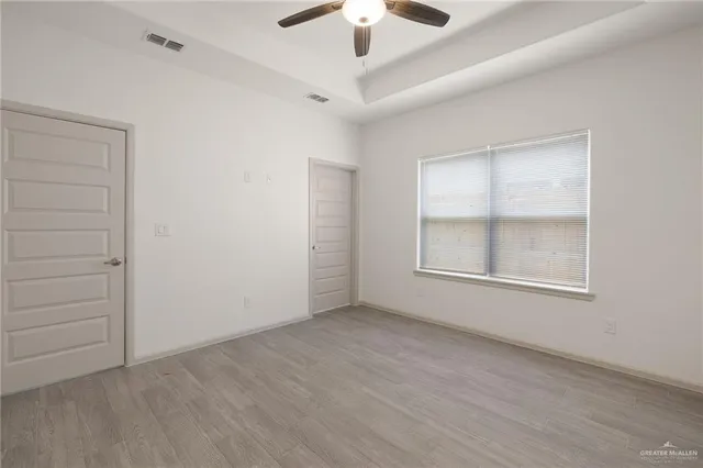an empty room with ceiling fan and window