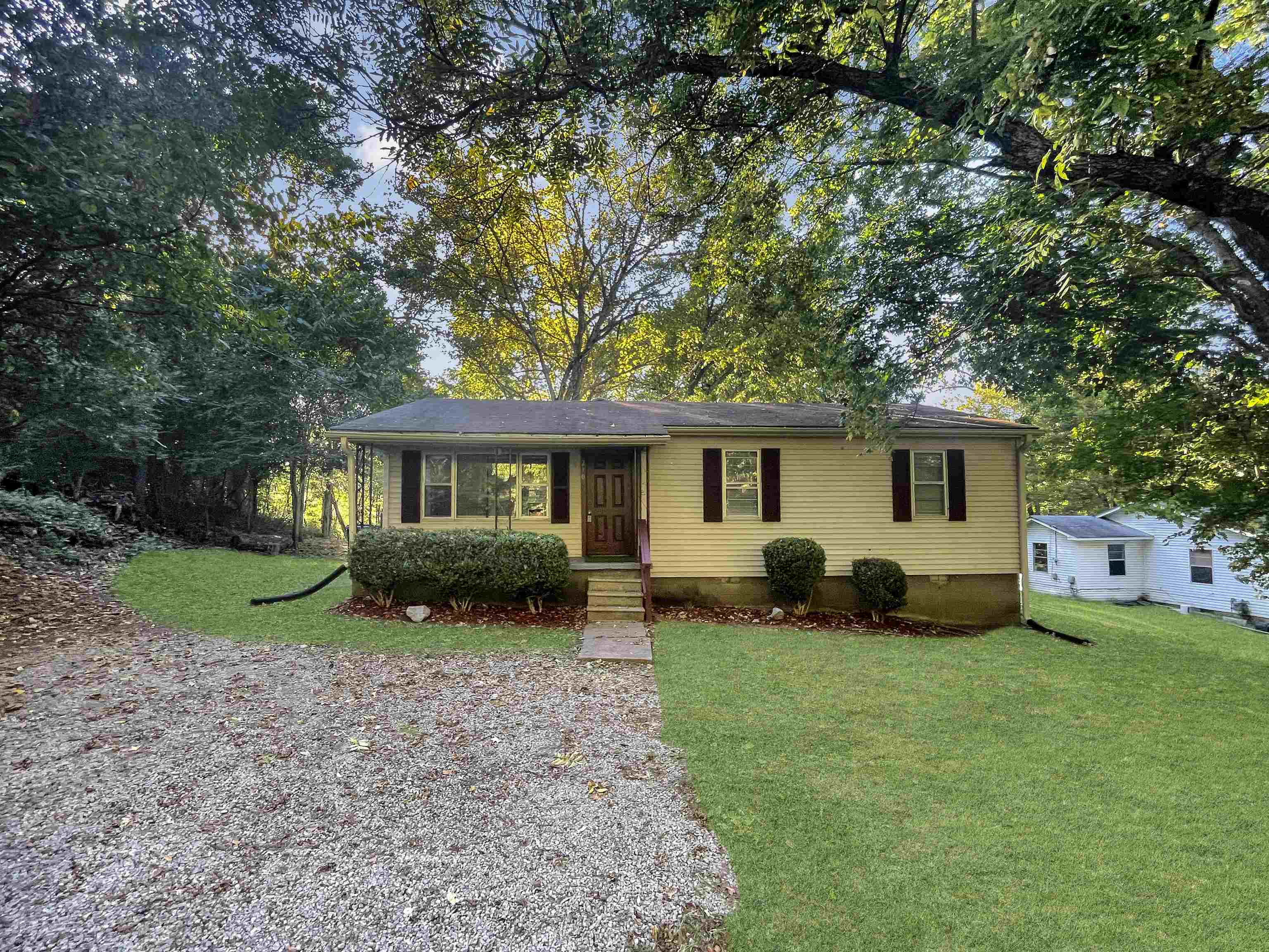 a front view of a house with a garden and trees