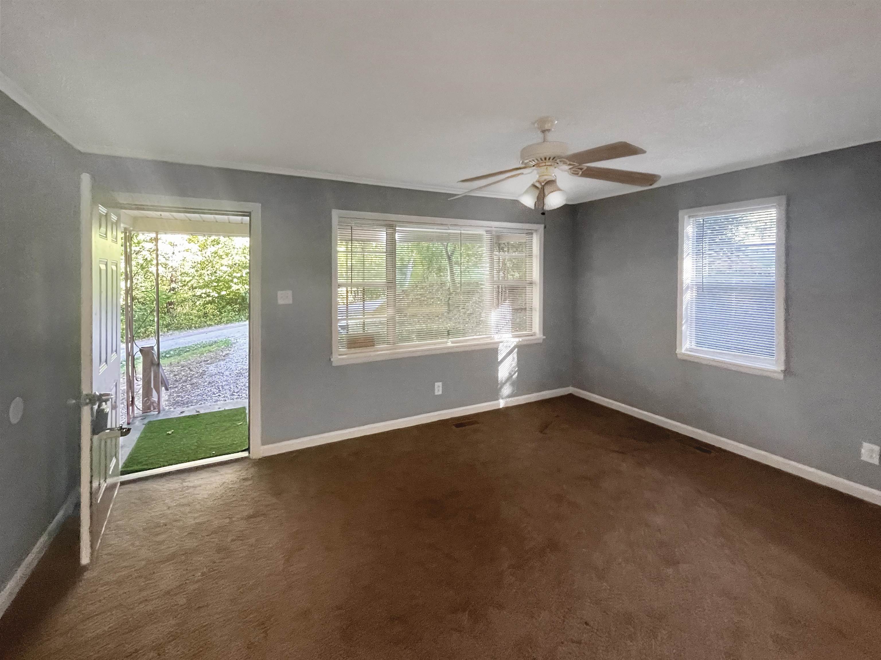 210 Tichenor Street Ripley, TN 38063 - Photo 3 of 10 an empty room with chandelier fan and windows