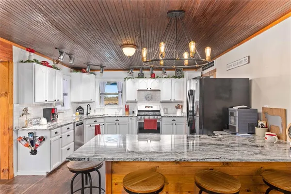 a kitchen with stainless steel appliances kitchen island granite countertop a sink dishwasher stove and refrigerator with wooden floor