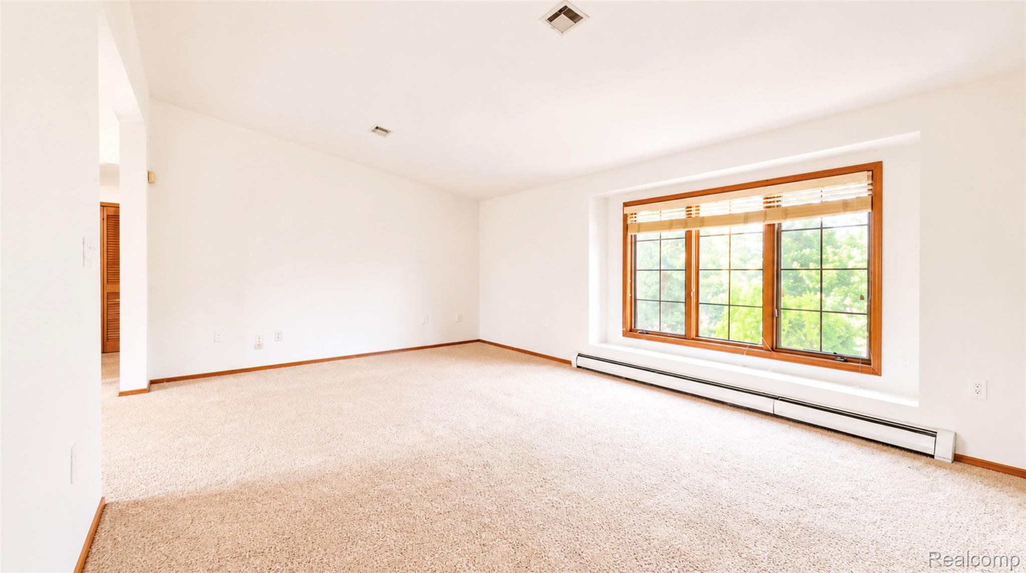 2232 London Bridge Drive, Unit 42 Rochester, MI 48307 - Photo 2 of 20 Carpeted room with a prominent bay window featuring wood trim