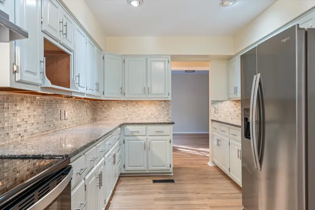 a kitchen with granite countertop wooden cabinets stainless steel appliances and a wooden floor