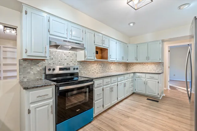 a kitchen with granite countertop white cabinets and stainless steel appliances