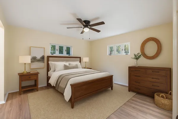 an empty room with wooden floor ceiling fan and windows