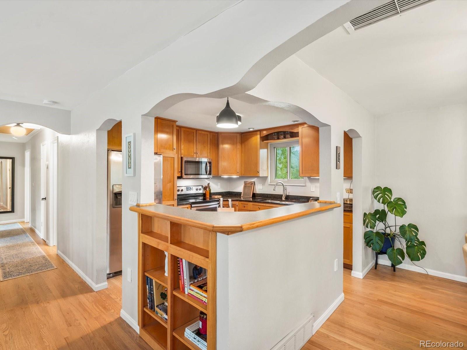 8324 Everett Way Arvada, CO 80005 - Photo 11 of 39 a kitchen with stainless steel appliances granite countertop a stove a refrigerator and a dining table