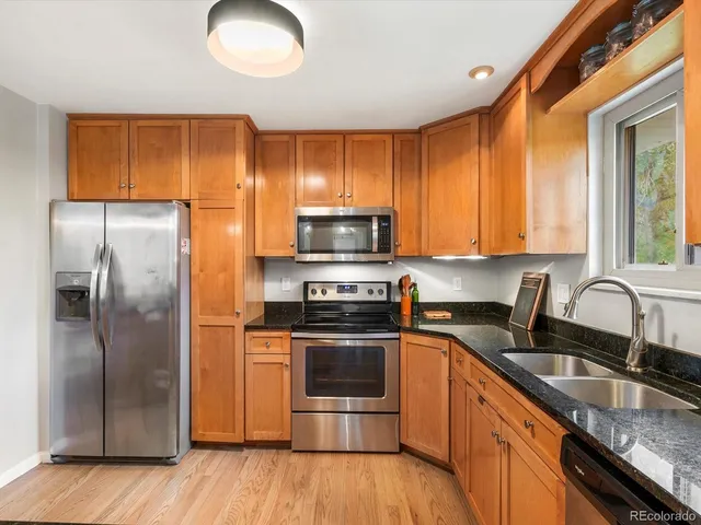 a kitchen with granite countertop a sink stove and refrigerator