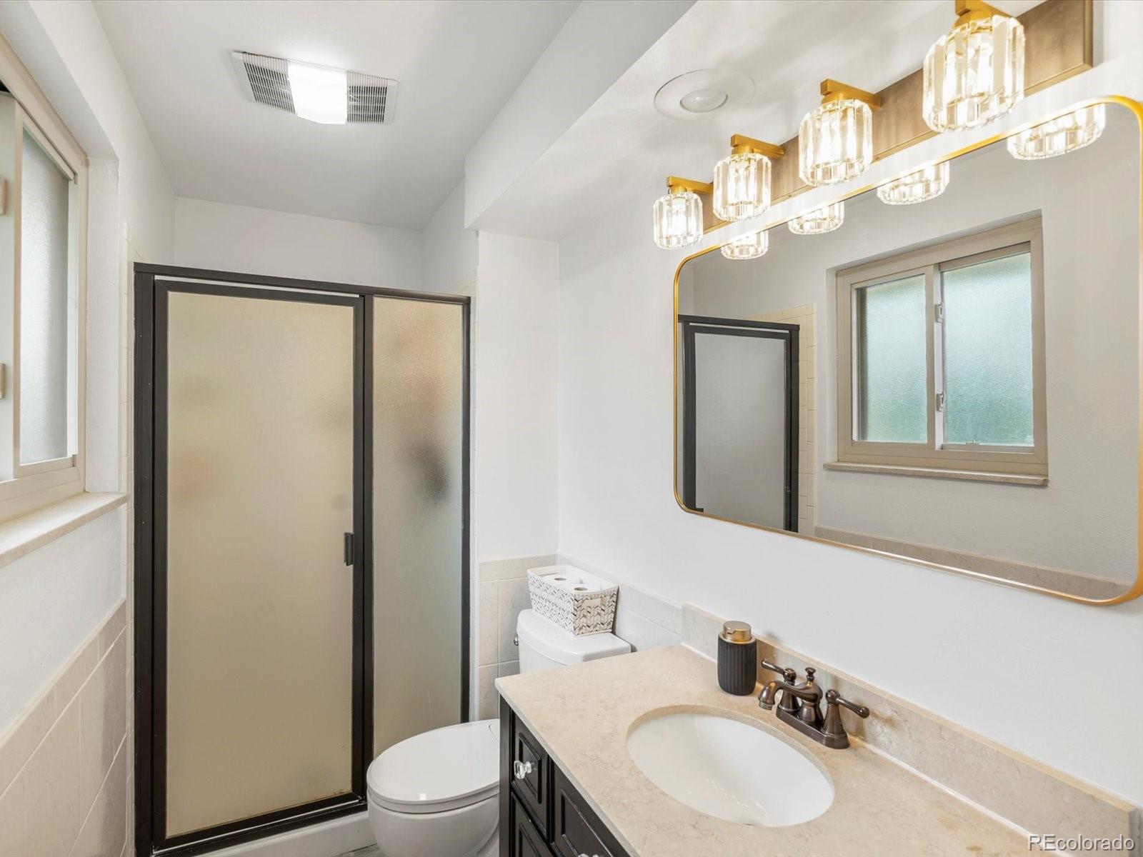 8324 Everett Way Arvada, CO 80005 - Photo 13 of 39 a bathroom with a granite countertop sink toilet a mirror and shower