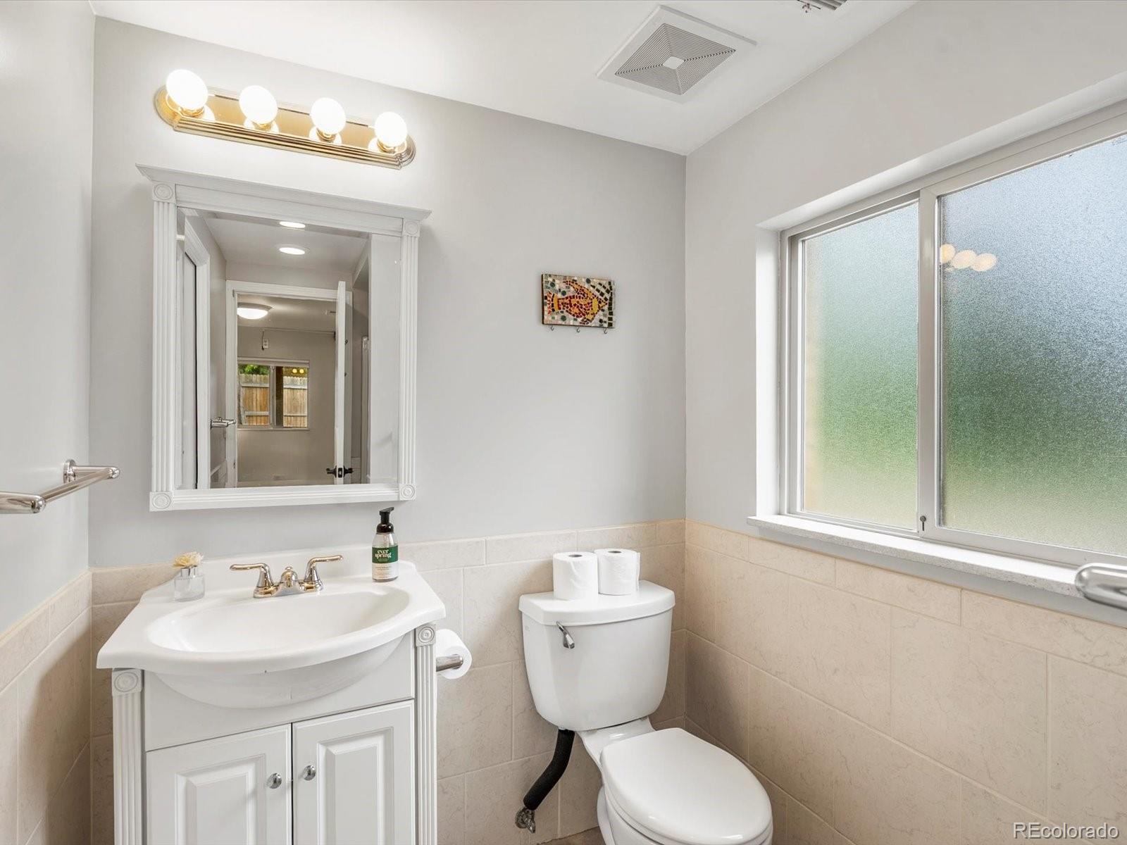 8324 Everett Way Arvada, CO 80005 - Photo 22 of 39 a bathroom with a toilet sink and mirror