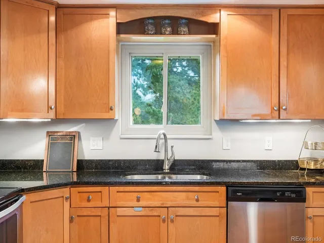 a kitchen with granite countertop a sink a stove and cabinets