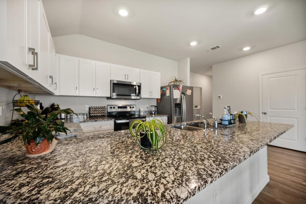 909 Avagail Avenue Springtown, TX 76082 - Photo 9 of 26 a kitchen with stainless steel appliances granite countertop a sink a stove and a wooden cabinets