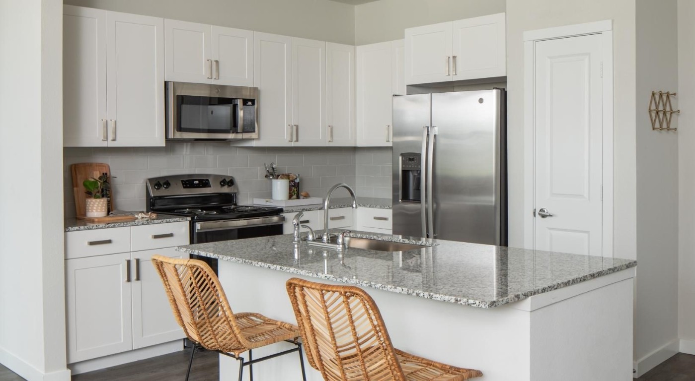 a kitchen with stainless steel appliances granite countertop a sink a stove and a refrigerator