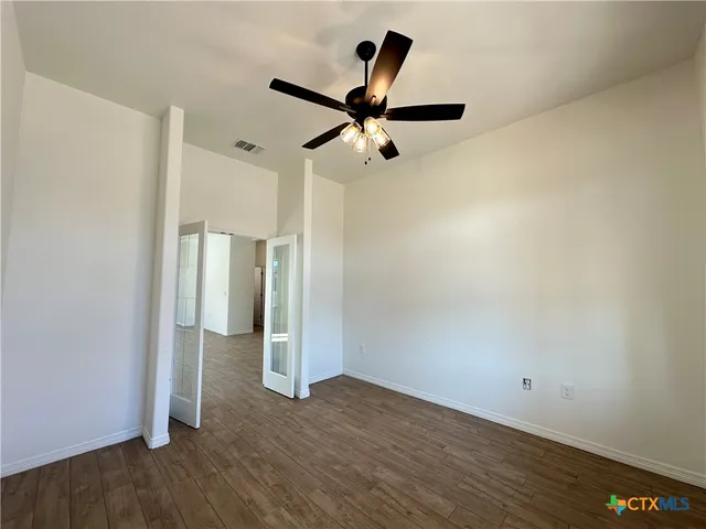 a view of empty room with wooden floor and ceiling fan