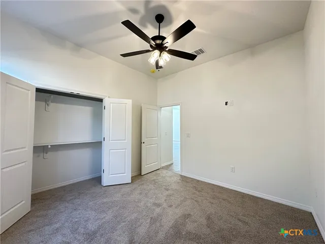 an empty room with closet and ceiling fan