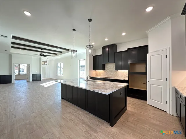 a large kitchen with stainless steel appliances a large counter top and wooden floor