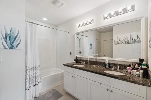 a spacious bathroom with a double vanity sink a large mirror and a bathtub