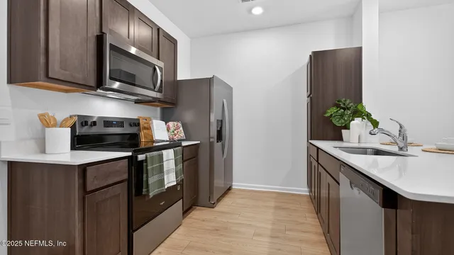 a kitchen with stainless steel appliances granite countertop a refrigerator a stove a sink and a microwave