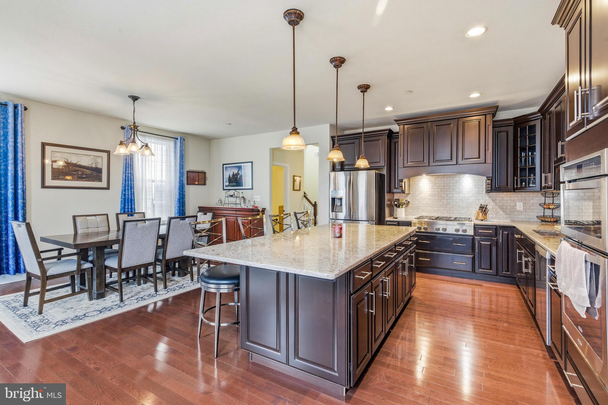 309 Corvus Circle Springfield, PA 19064 - Photo 8 of 34 a open kitchen with stainless steel appliances granite countertop a stove top oven a sink dishwasher a dining table and chairs with wooden floor