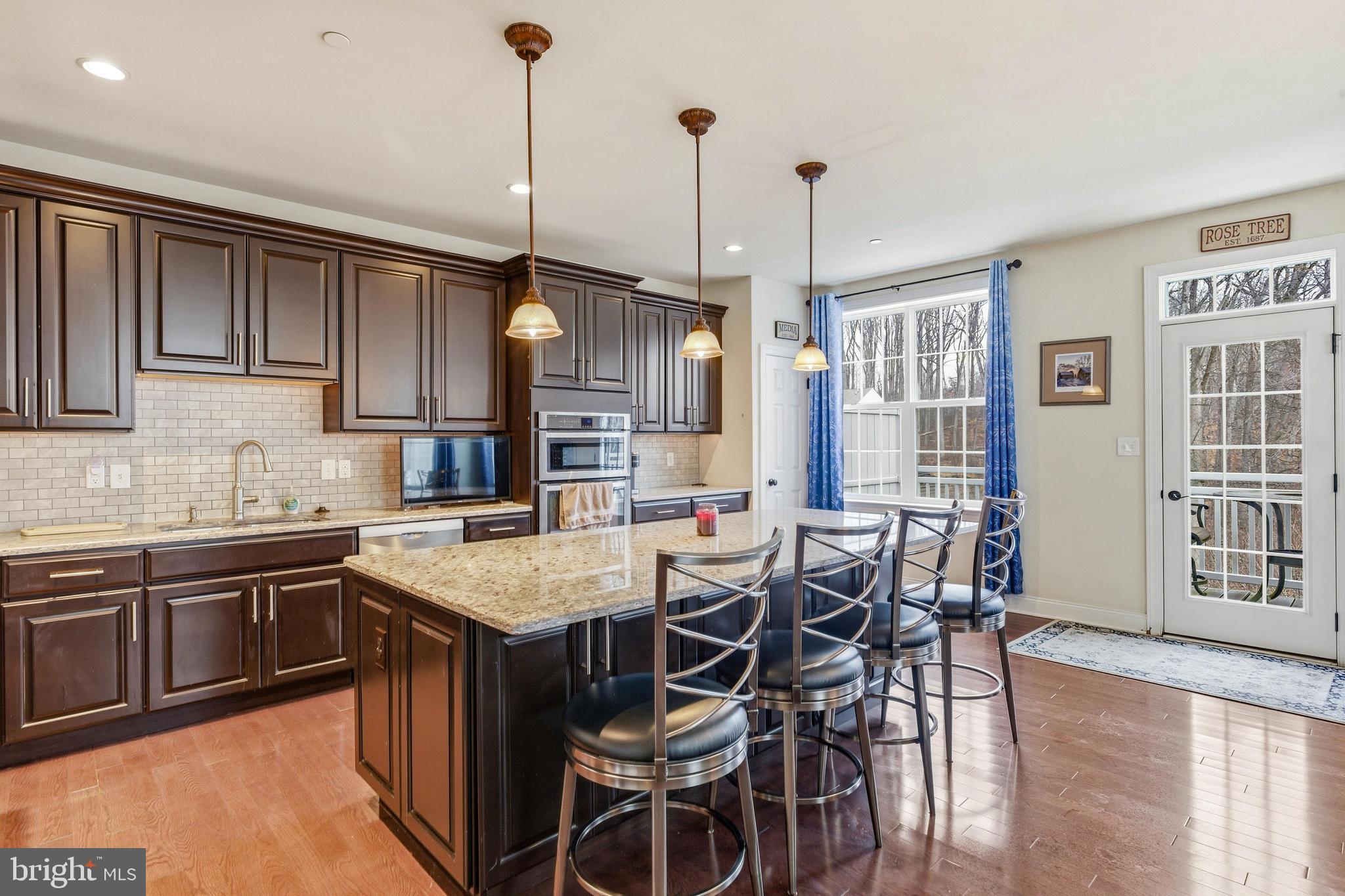 309 Corvus Circle Springfield, PA 19064 - Photo 10 of 34 a kitchen with stainless steel appliances granite countertop a stove top oven a sink a dining table and chairs with wooden floor