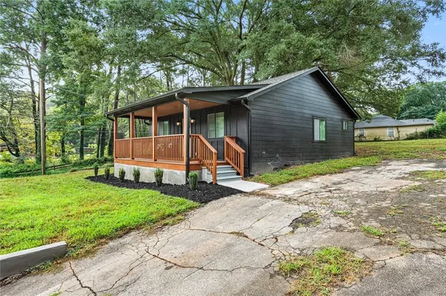 a view of backyard of house with wooden fence and large trees