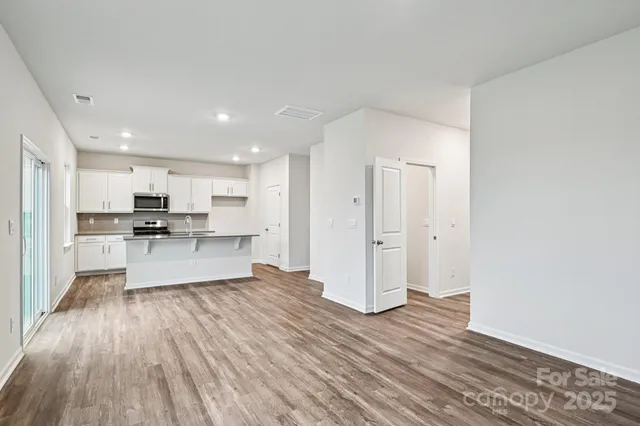 a living room with stainless steel appliances kitchen island hardwood floor and a view of kitchen