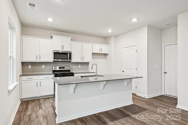 a kitchen with stainless steel appliances granite countertop a refrigerator and a stove top oven