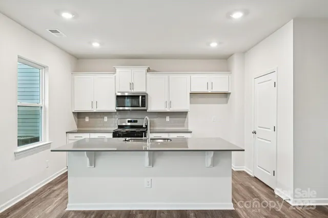 a kitchen with stainless steel appliances granite countertop a stove a sink and a microwave
