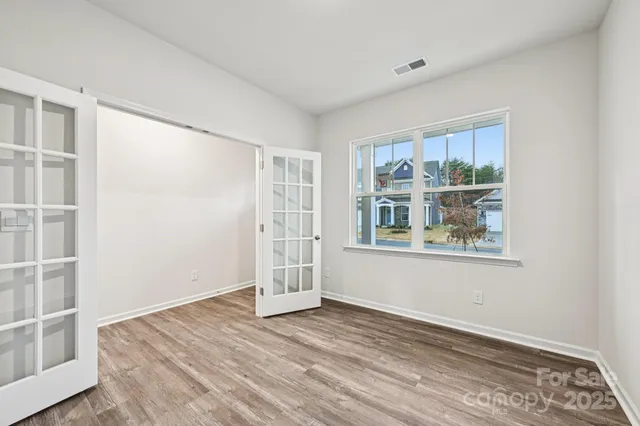 an empty room with wooden floor and windows