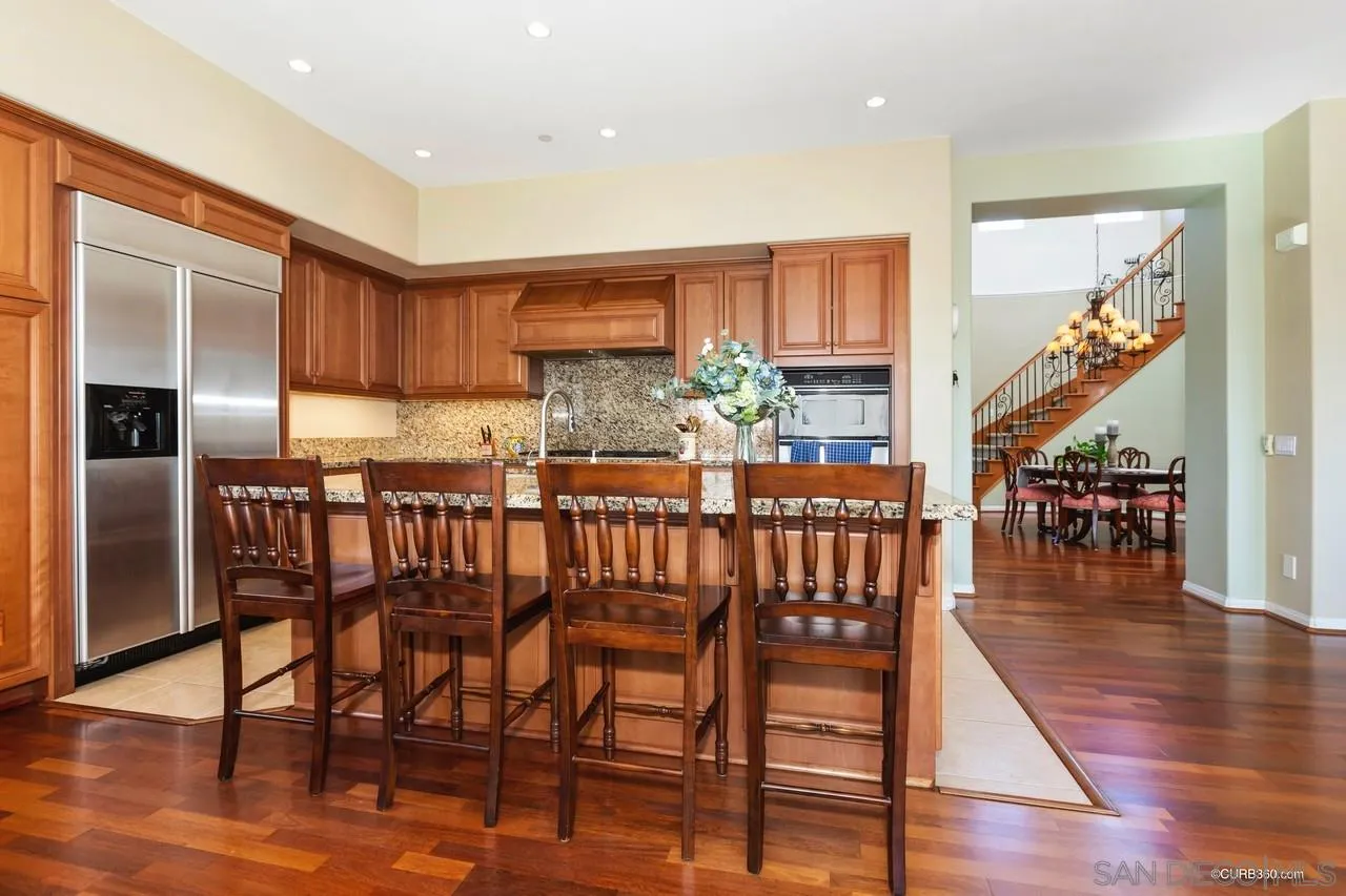 16290 Deer Ridge Road San Diego, CA 92127 - Photo 19 of 36 a kitchen with stainless steel appliances wooden floor dining table and chairs