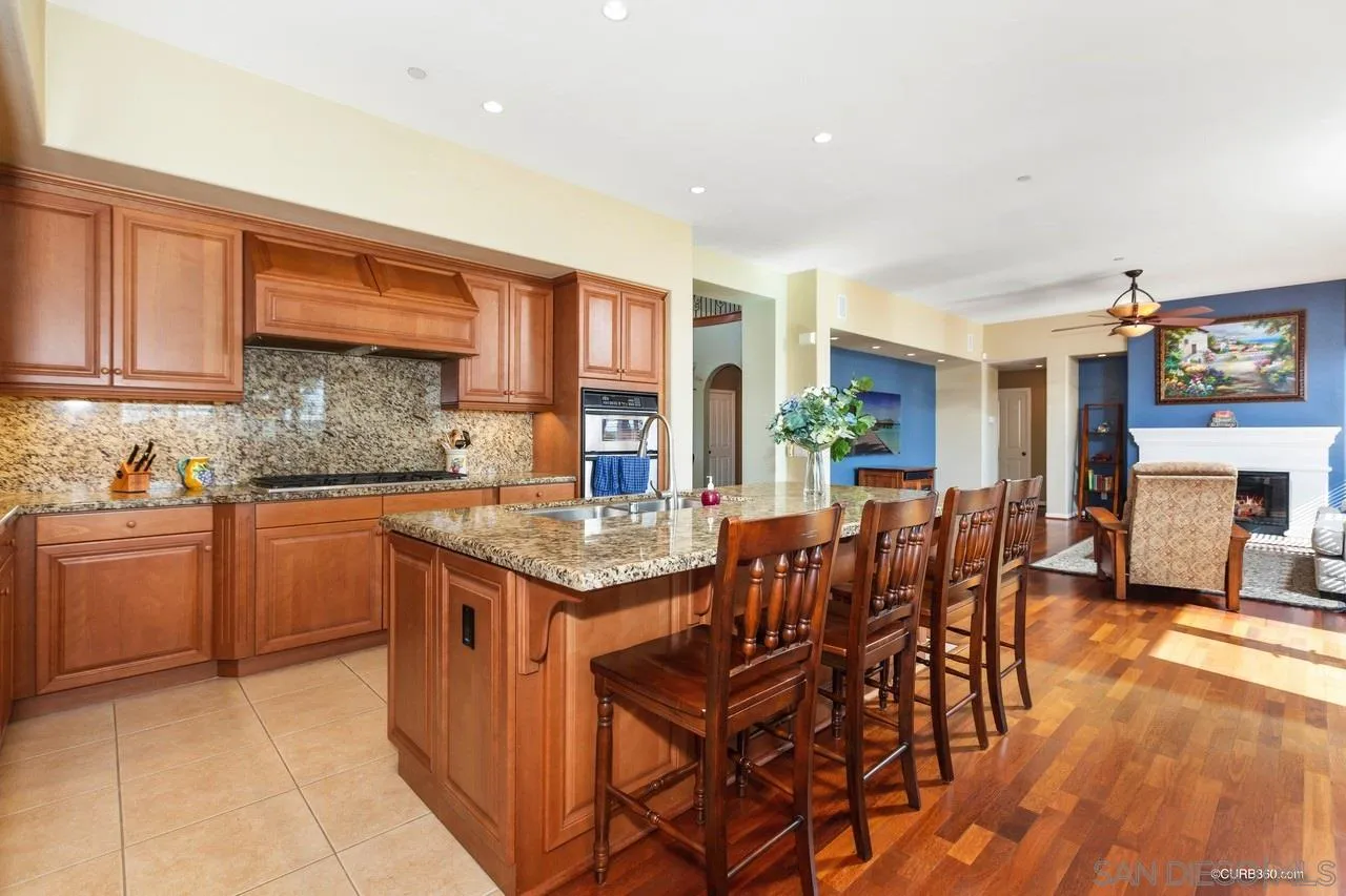 16290 Deer Ridge Road San Diego, CA 92127 - Photo 4 of 36 a kitchen with stainless steel appliances granite countertop a stove top oven a sink a dining table and chairs